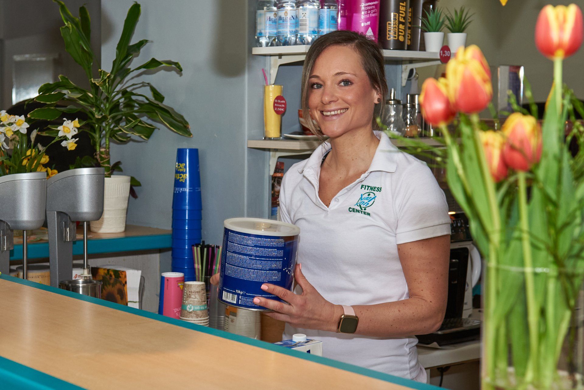 Eine Frau steht hinter einer Theke und hält einen Eimer Popcorn.