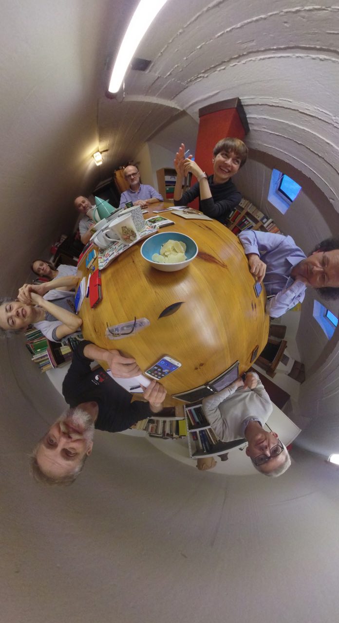 Un gruppo di persone è seduto attorno ad un tavolo su cui è posata una ciotola piena di cibo.