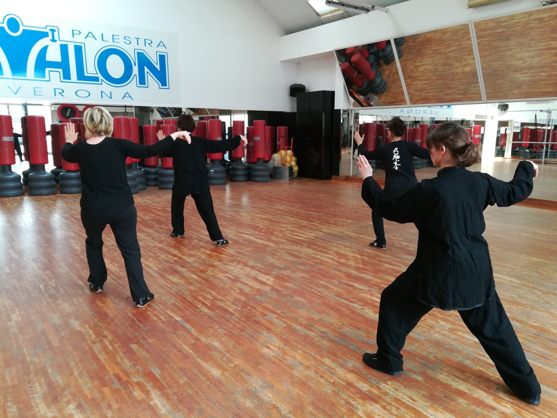 Un gruppo di persone pratica arti marziali in una palestra con un cartello che dice paleria yahon verona