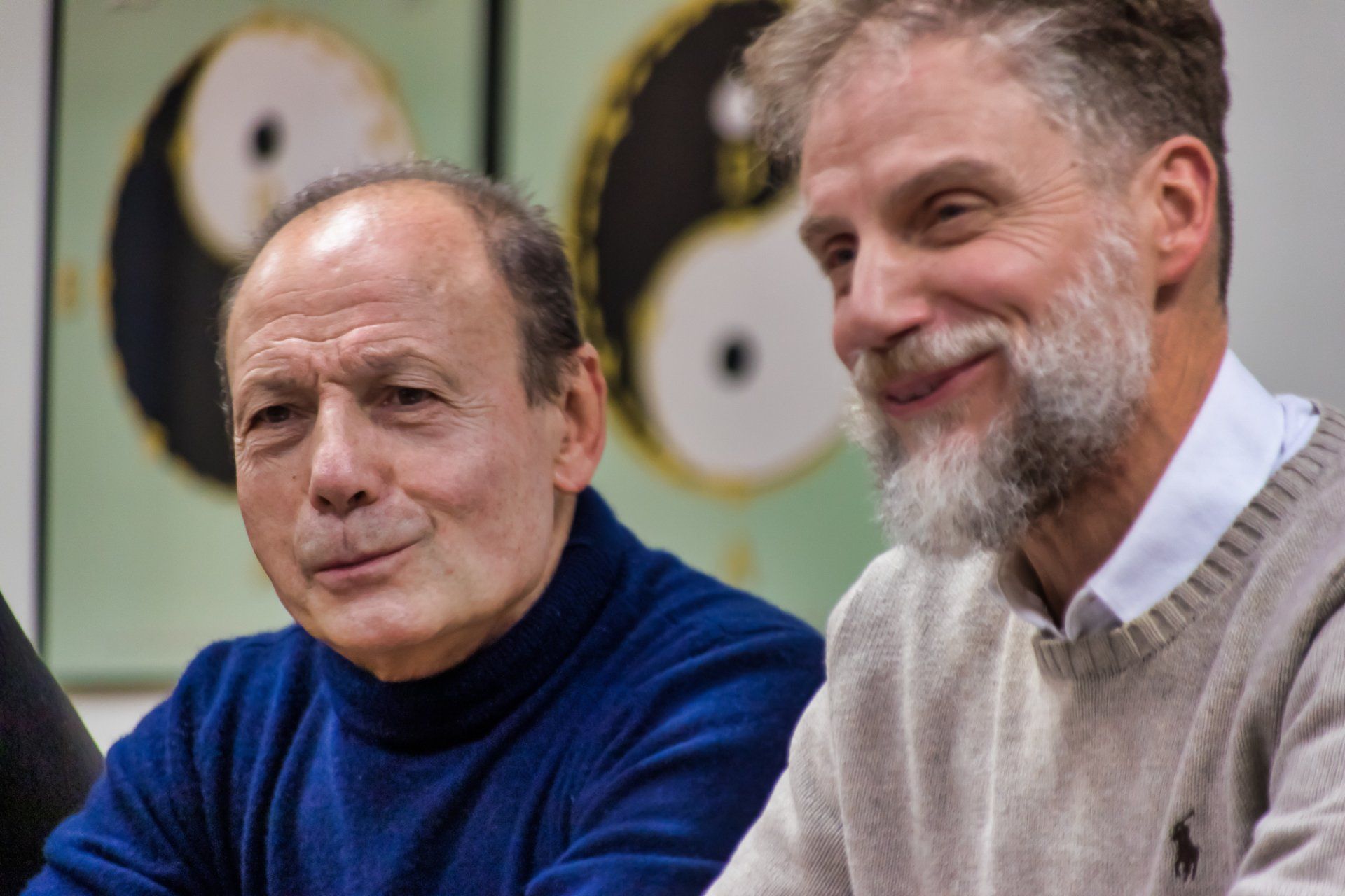 Due uomini sono seduti uno accanto all'altro davanti al simbolo dello yin yang.