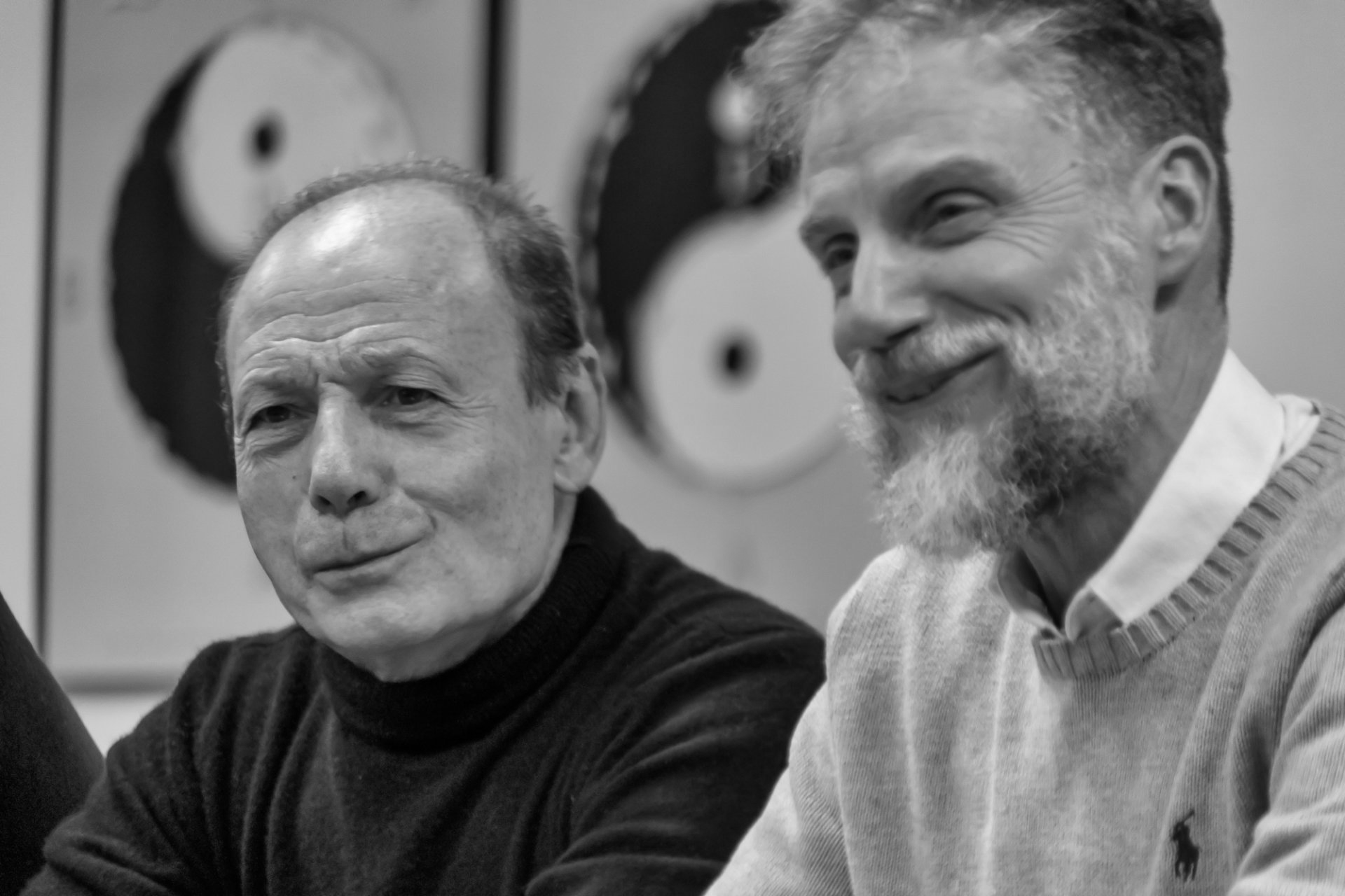 Due uomini sono seduti uno accanto all'altro e sorridono in una foto in bianco e nero.