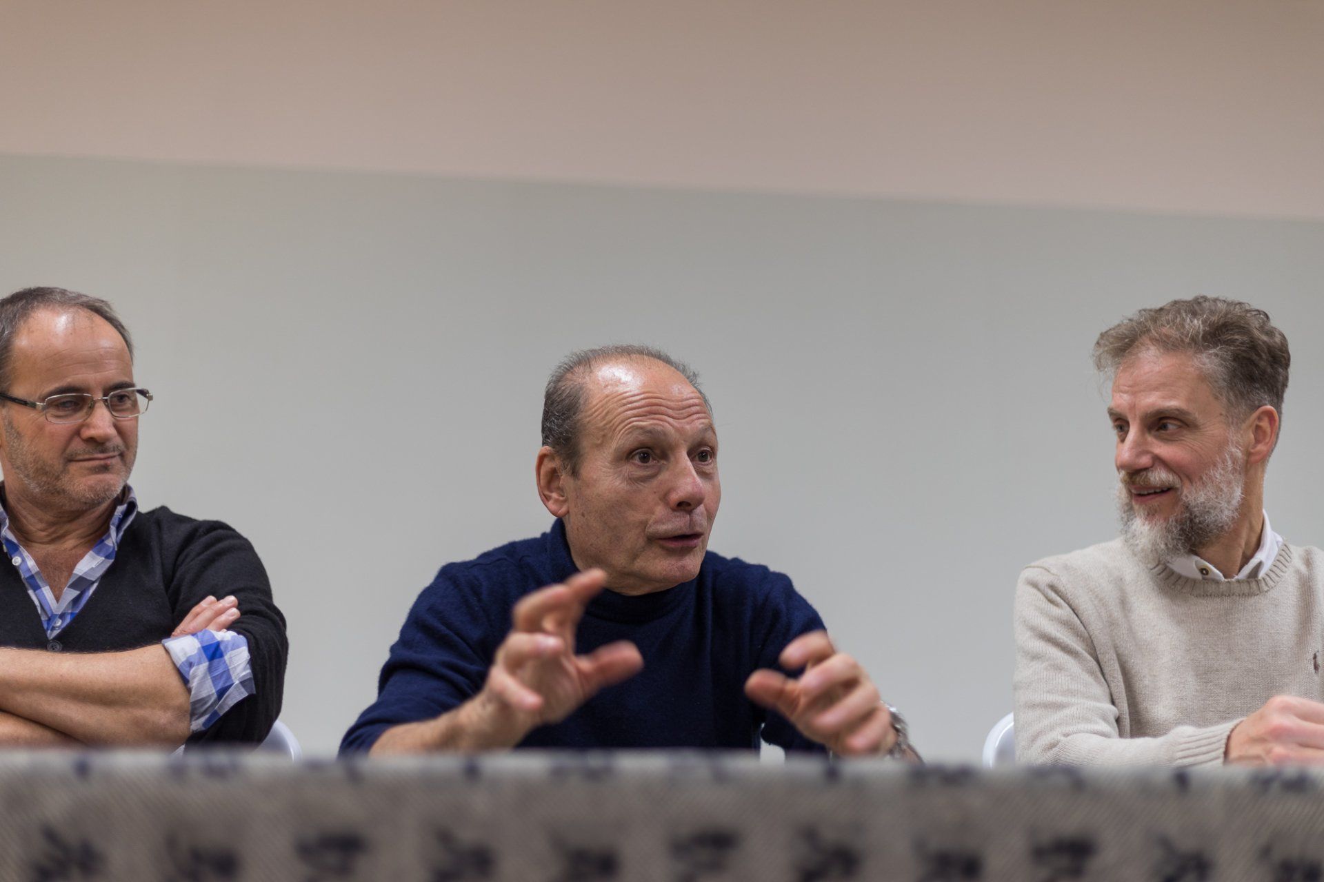 Tre uomini sono seduti a un tavolo e parlano tra loro.