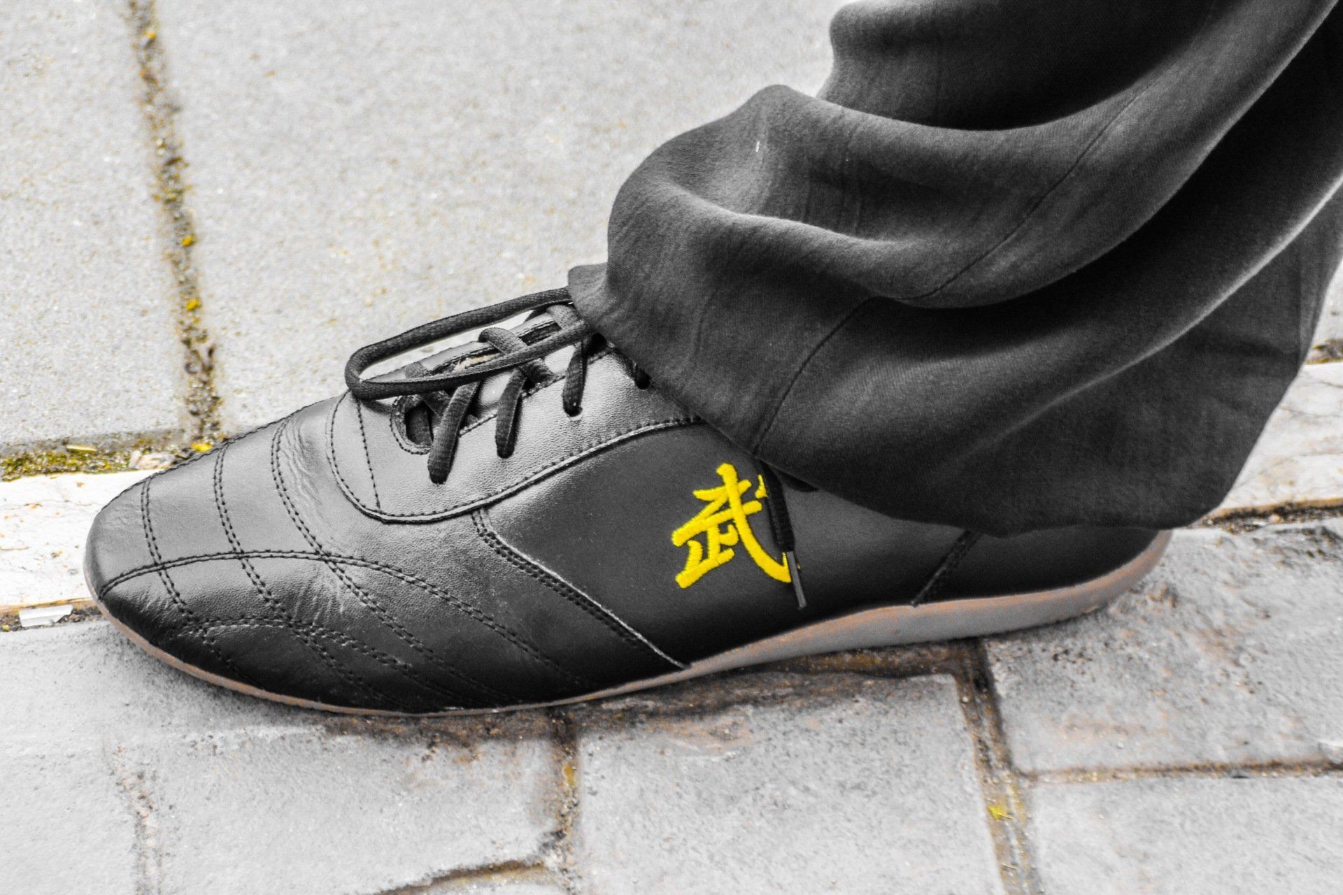 Una persona che indossa un paio di scarpe nere con caratteri cinesi sopra