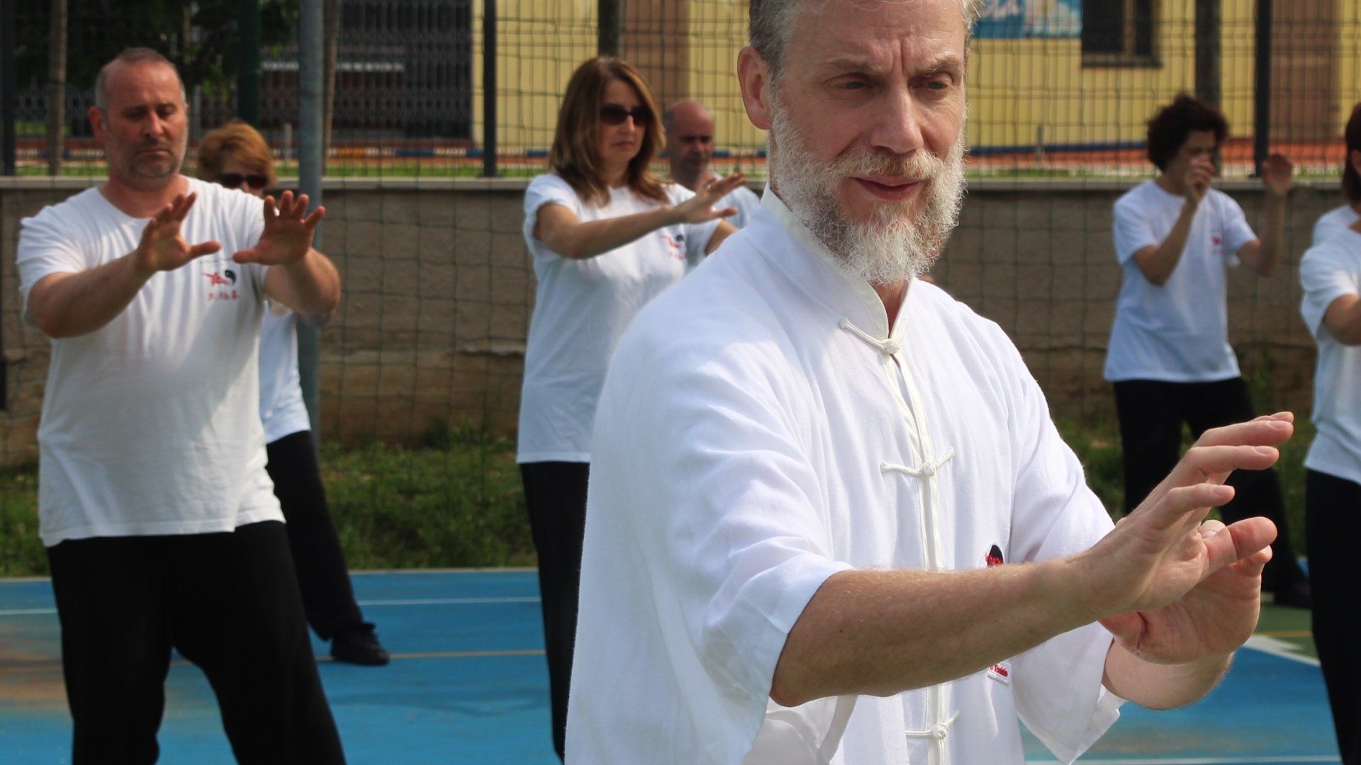 Un gruppo di persone pratica arti marziali su un campo blu.