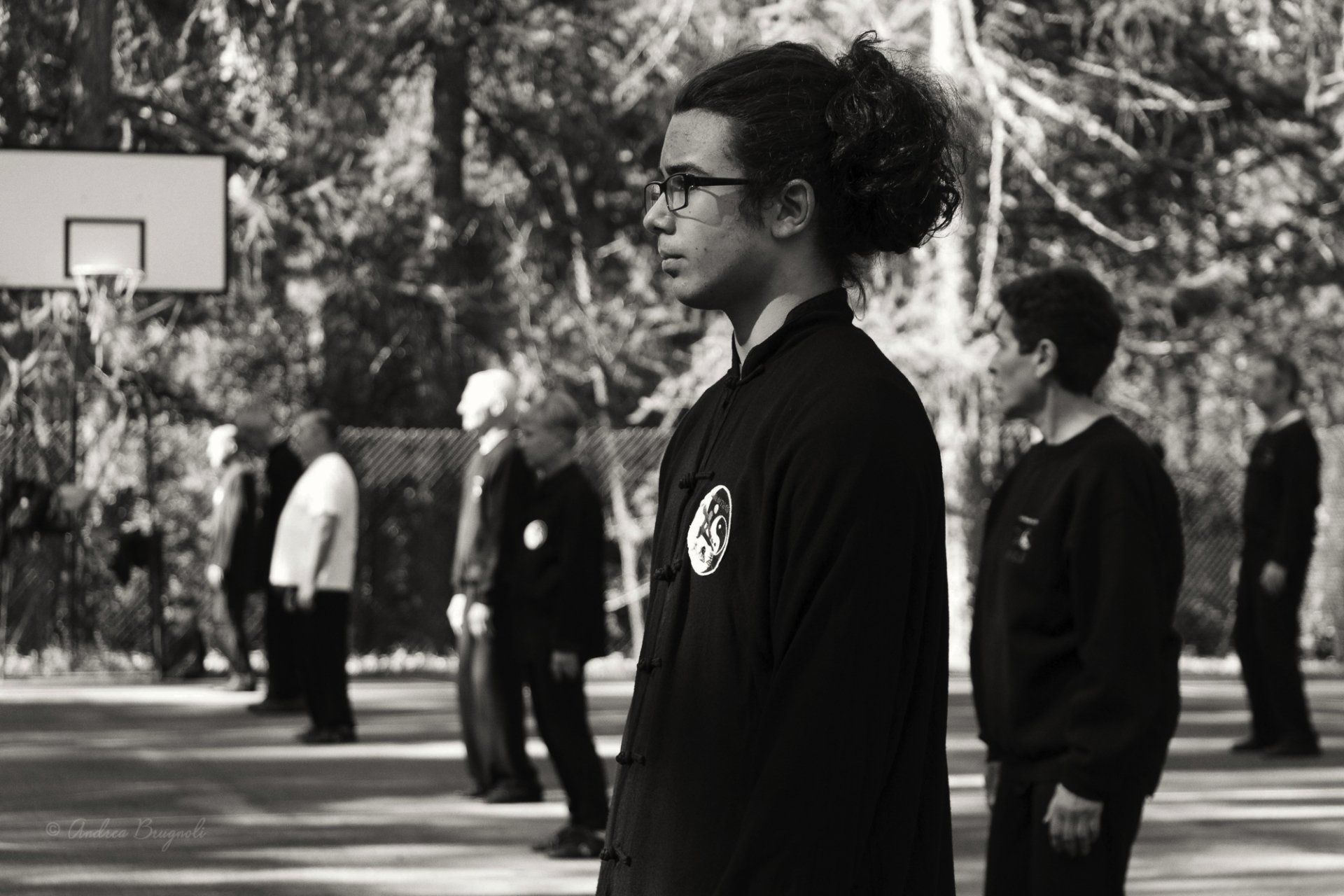 Una foto in bianco e nero di un gruppo di persone in piedi davanti a un canestro da basket.