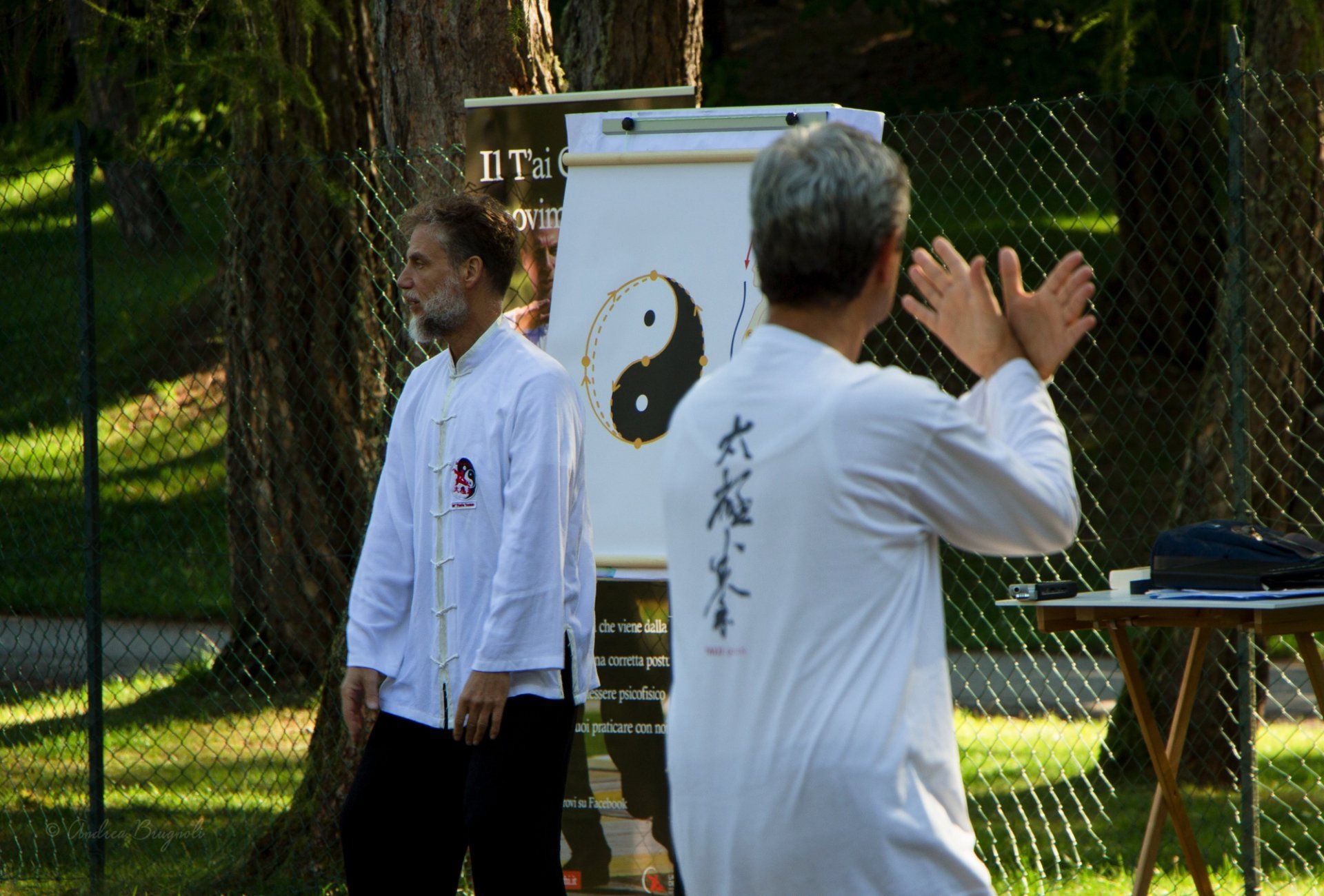 Due uomini sono in piedi davanti a un cartello con sopra il simbolo dello yin yang