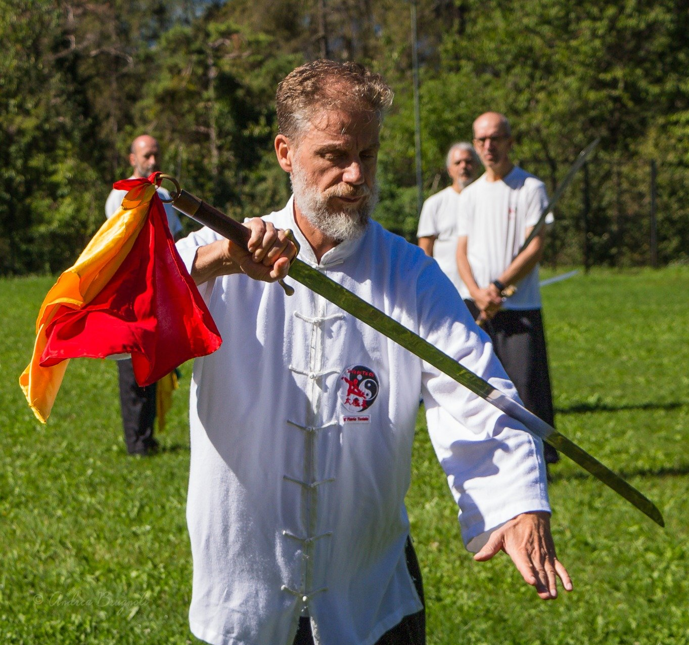 Un uomo con la barba tiene in mano un palo in un campo