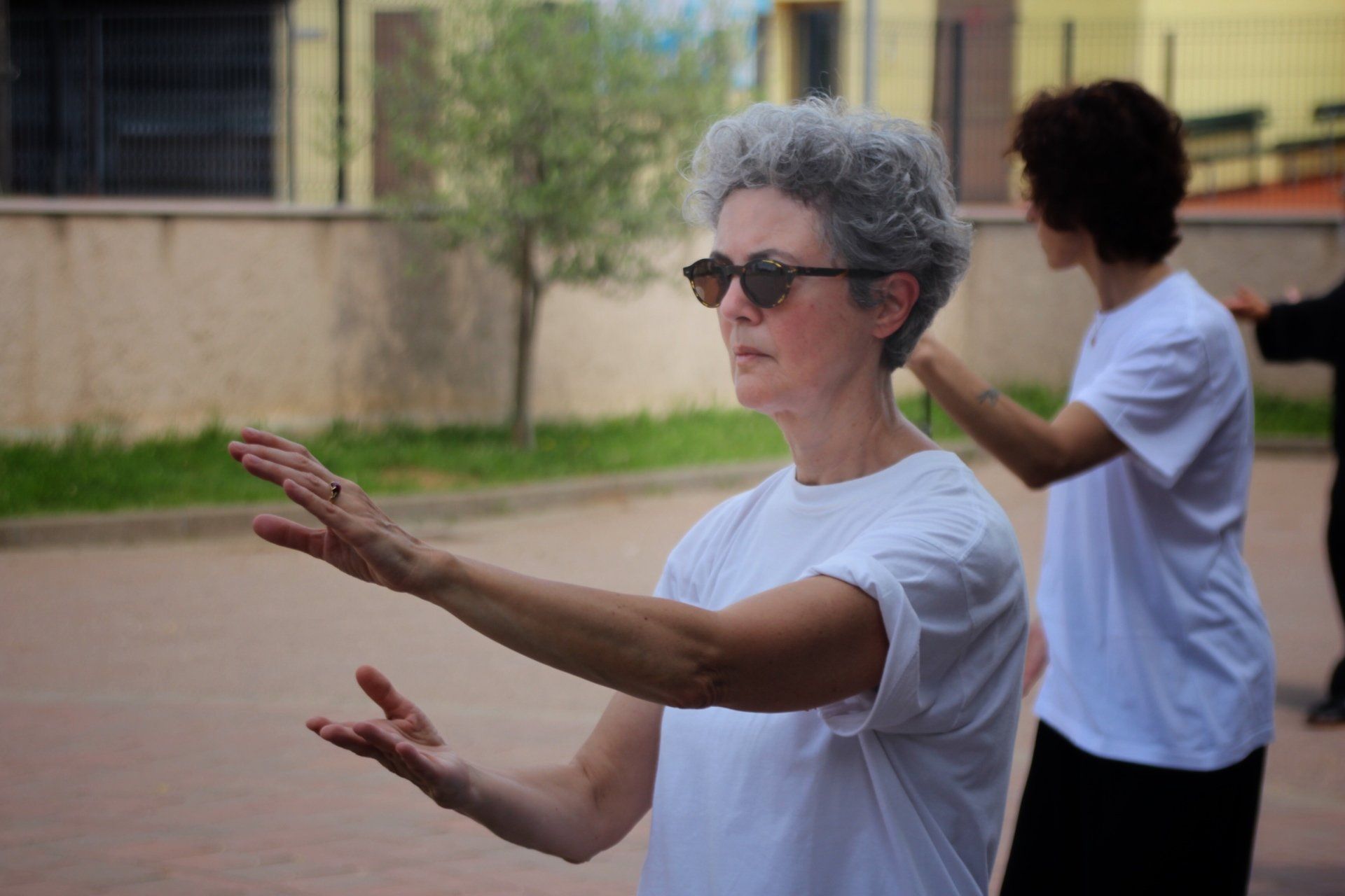 Una donna che indossa occhiali da sole e una camicia bianca pratica arti marziali.
