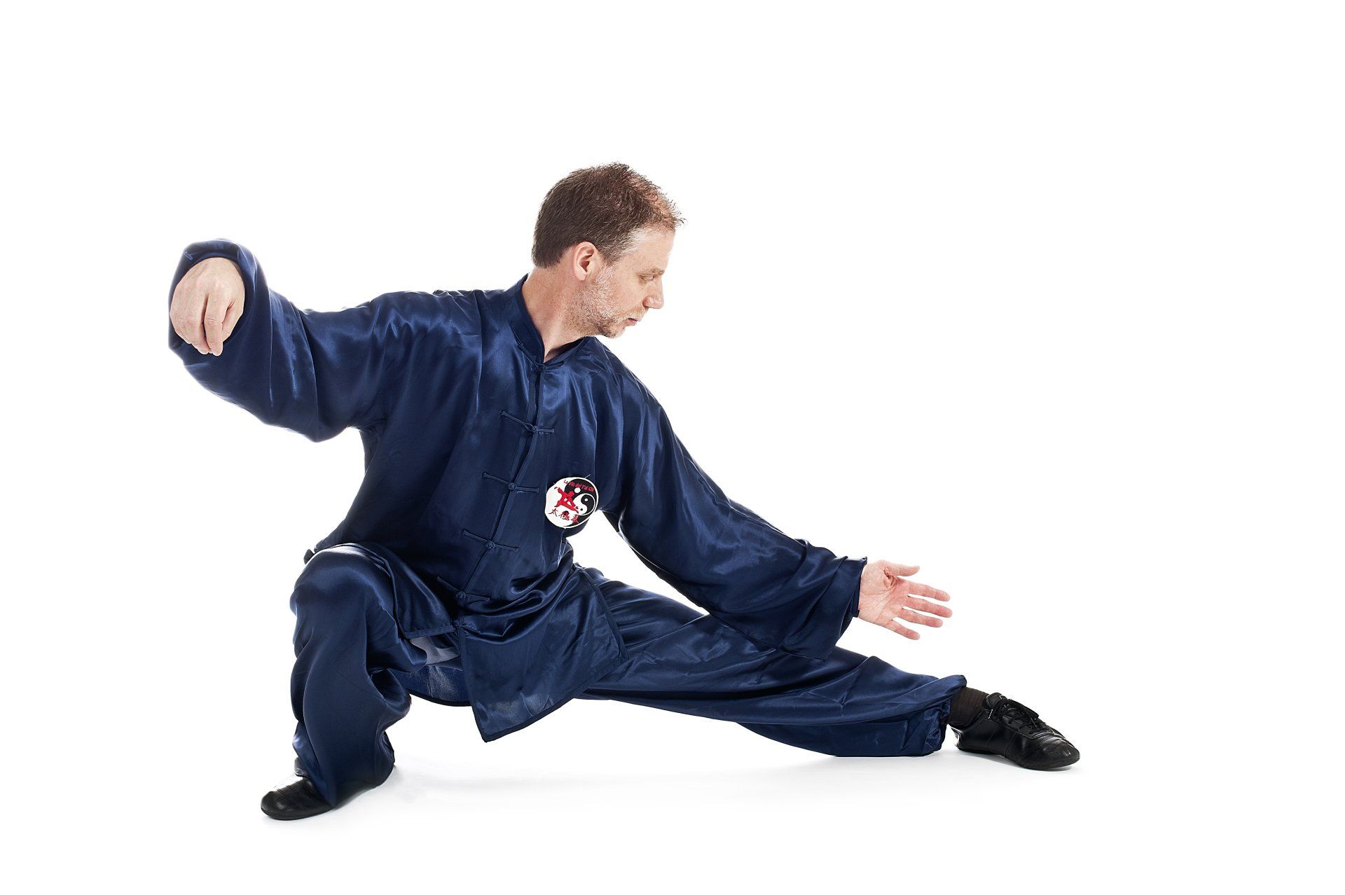 Un uomo vestito di blu pratica arti marziali su sfondo bianco.
