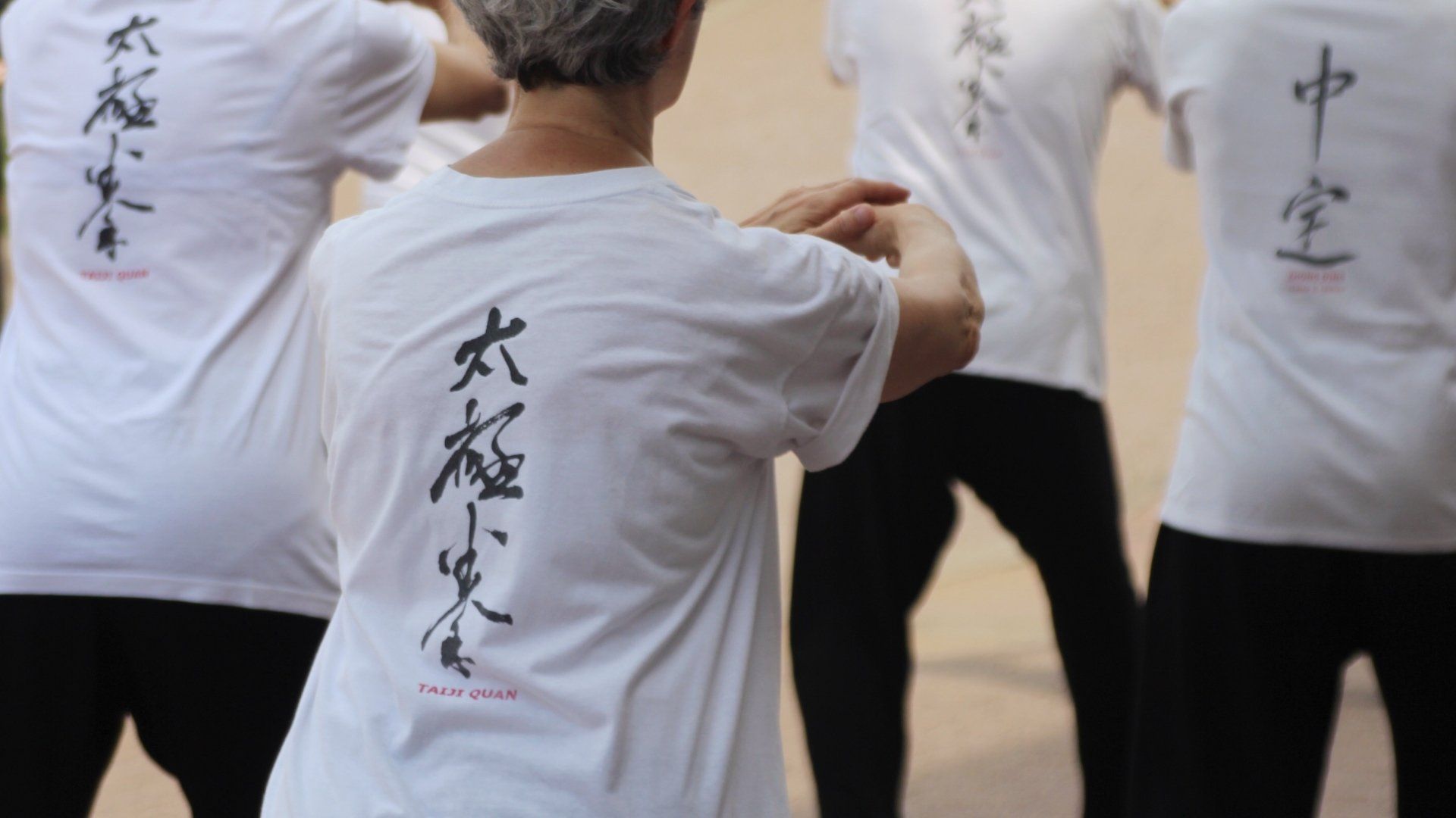 Un gruppo di persone che indossano camicie bianche con scritte cinesi sopra