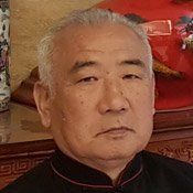 Primo piano del volto di un uomo con un vaso sullo sfondo.