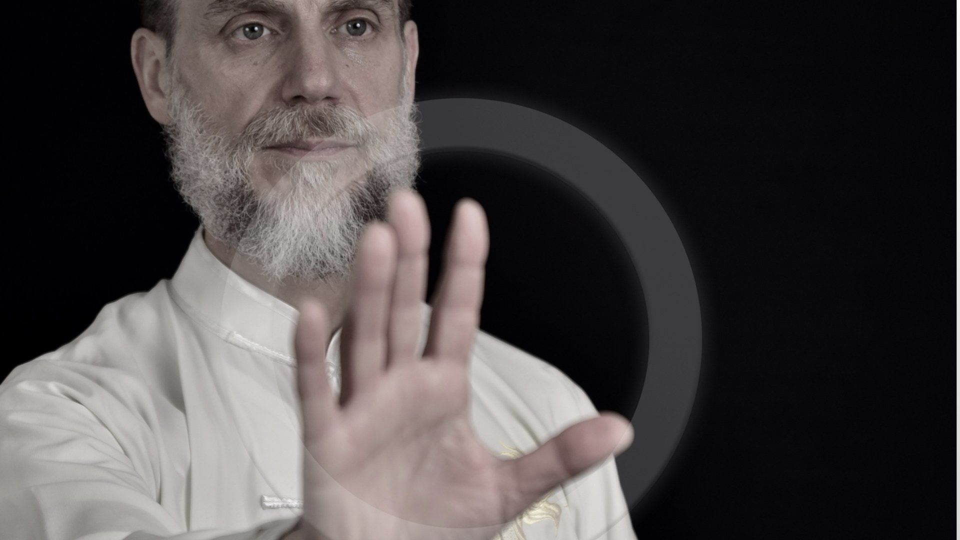 Un uomo con la barba fa un segnale di stop con la mano.