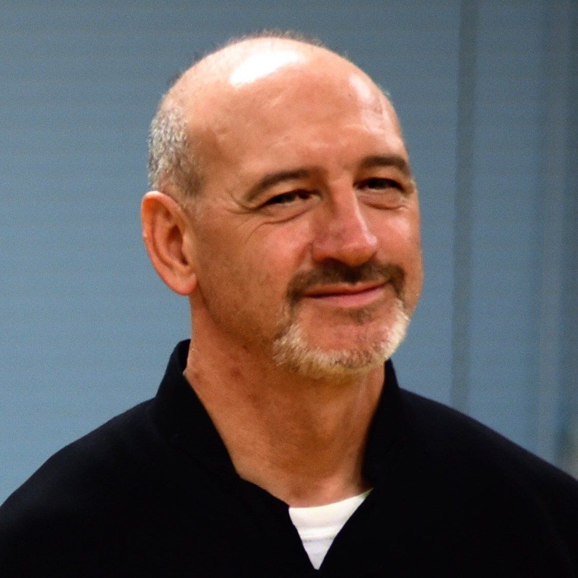 Un uomo calvo con la barba che indossa una camicia nera