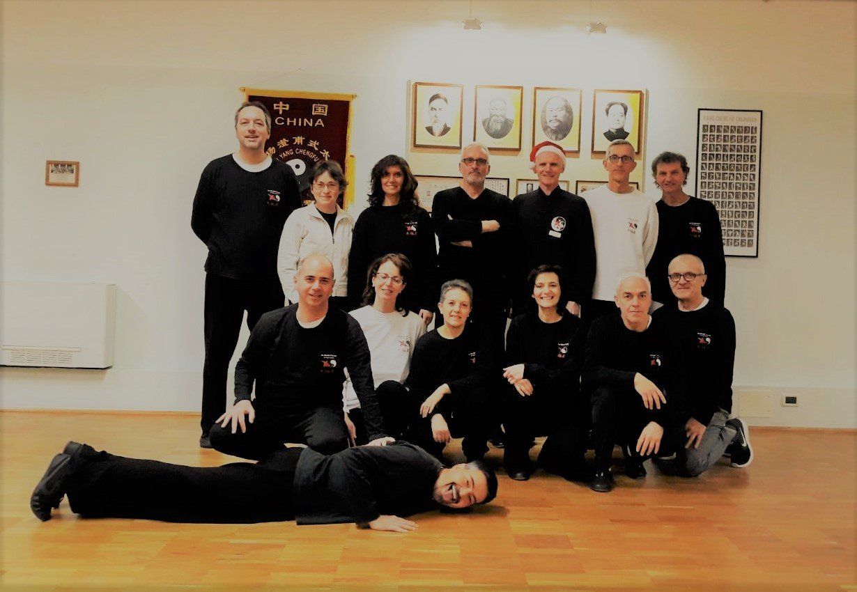 Un gruppo di persone in posa per una foto con un uomo sdraiato sul pavimento