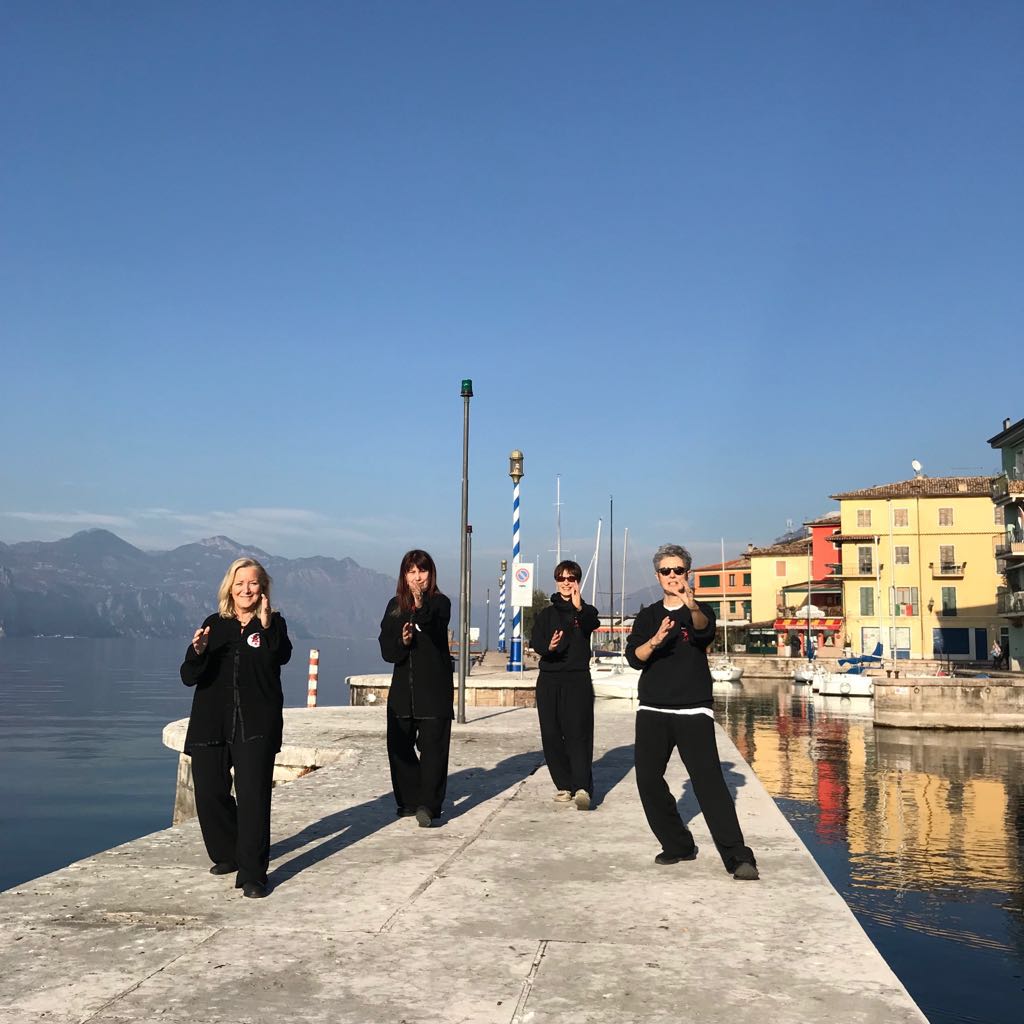 Un gruppo di persone è in piedi su un molo vicino a uno specchio d'acqua.