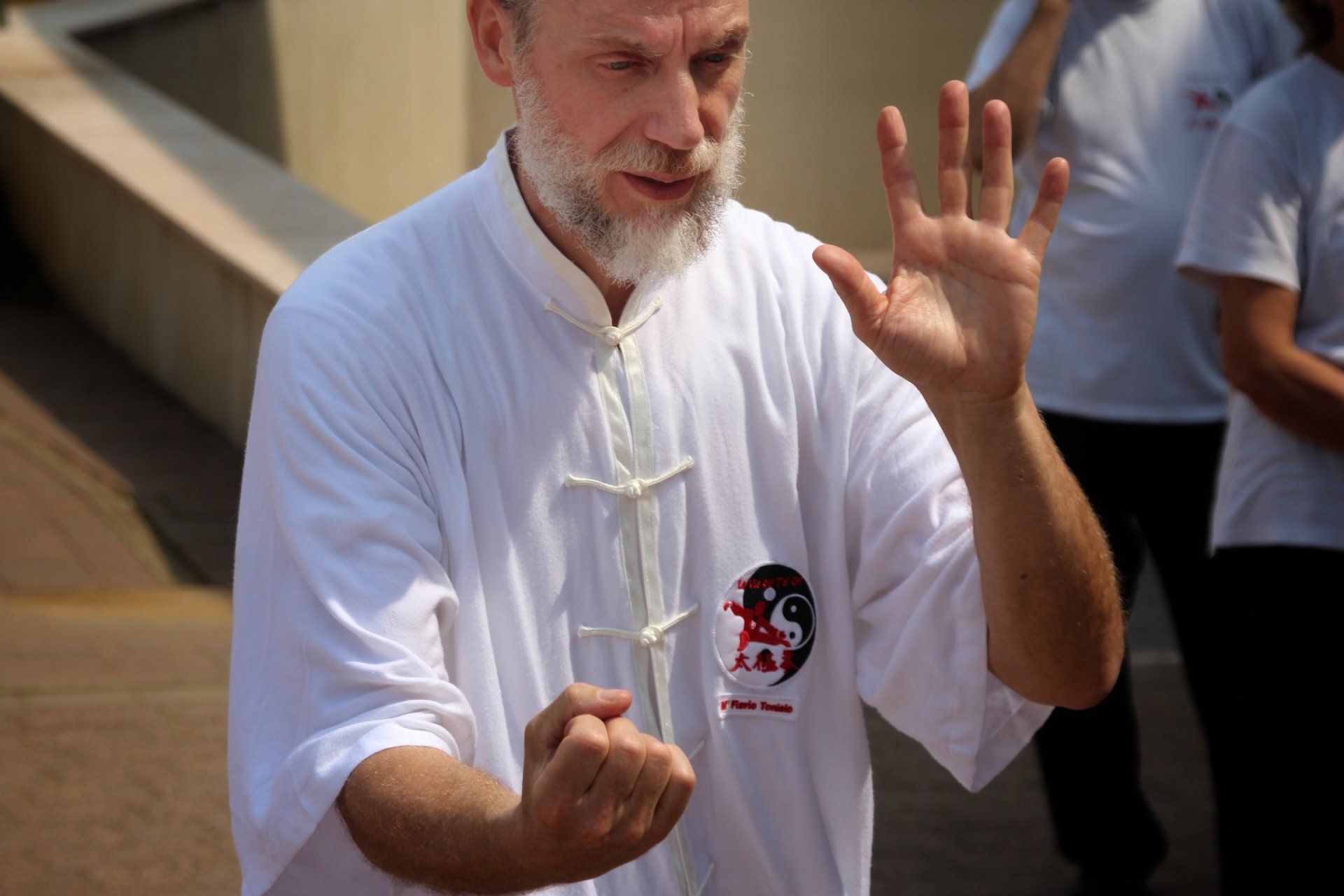 Un uomo con la barba indossa una camicia bianca con sopra la lettera s