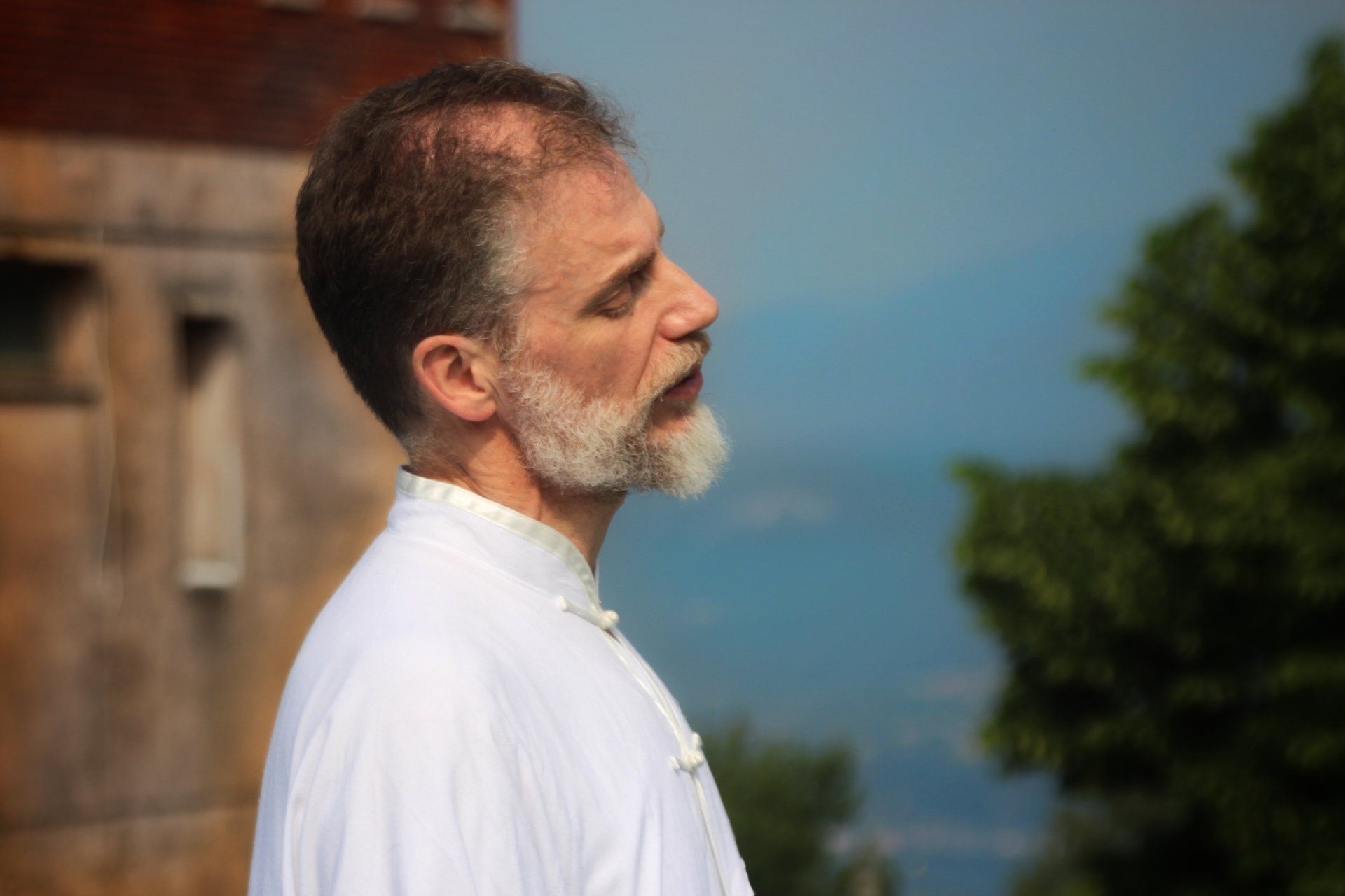 Un uomo con la barba è in piedi con gli occhi chiusi