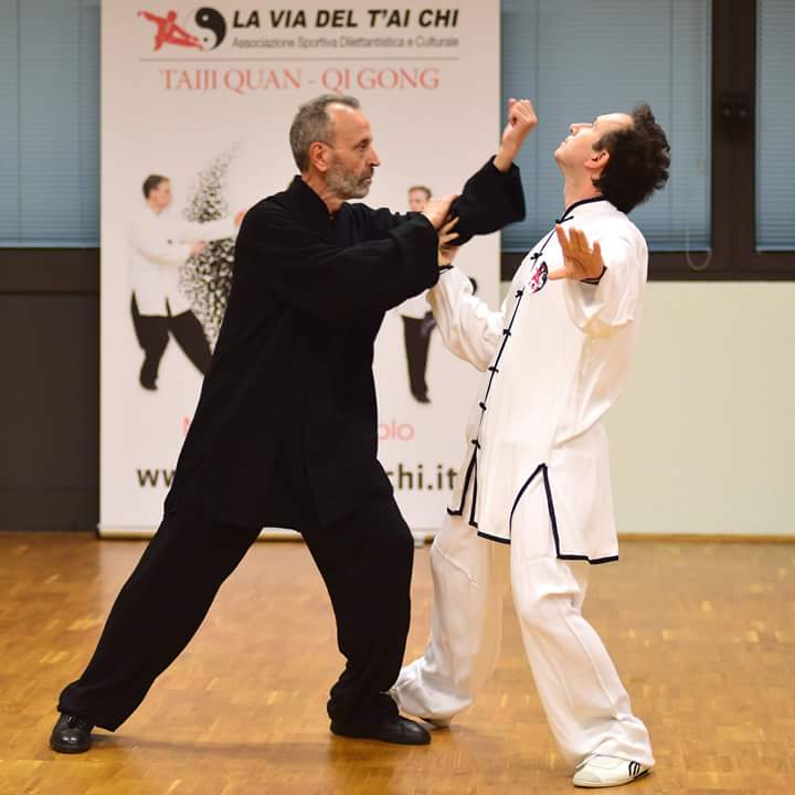 Due uomini praticano arti marziali davanti ad un cartello che dice la via del tai chi