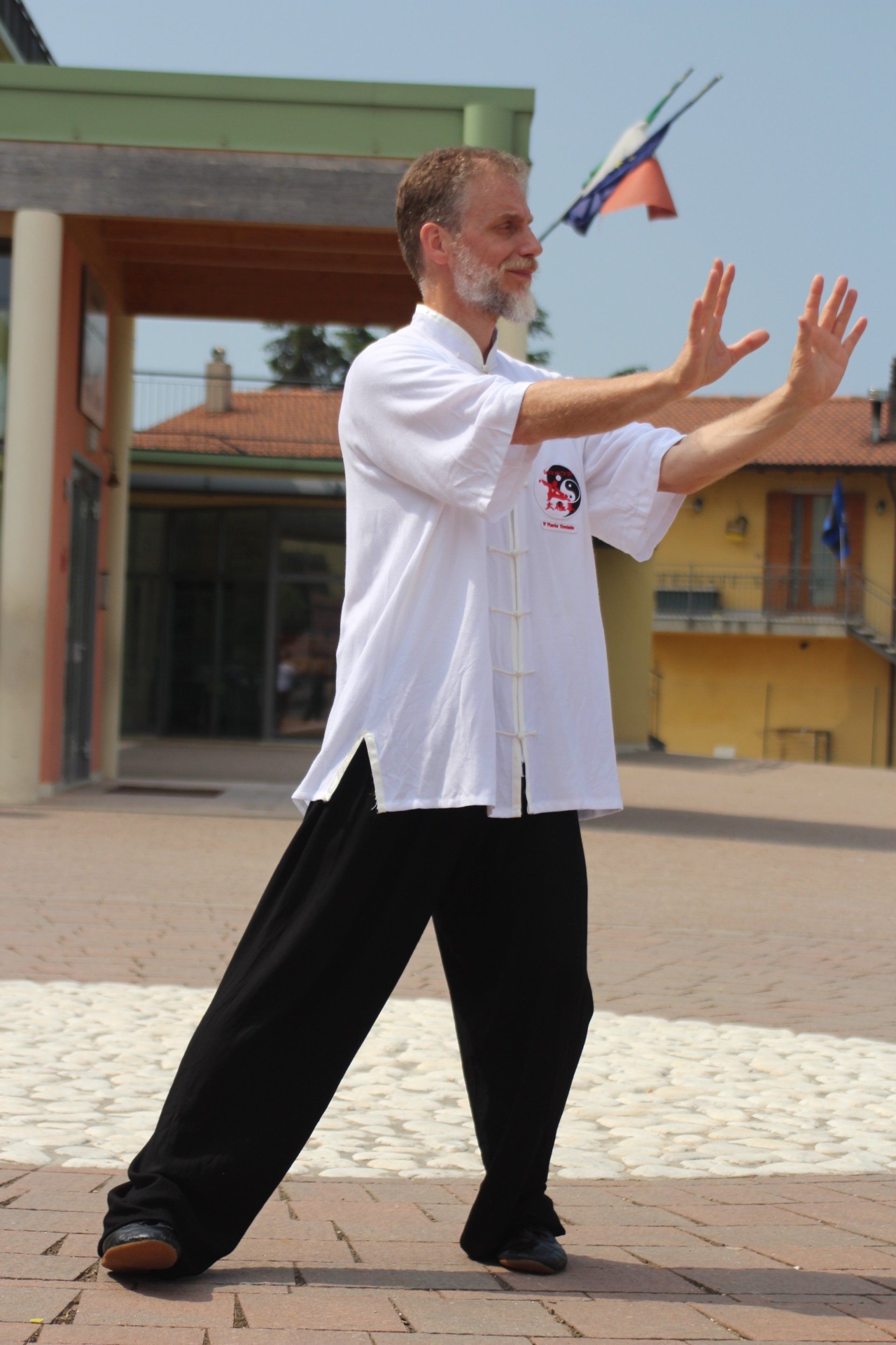 Un uomo con una camicia bianca e pantaloni neri pratica le arti marziali