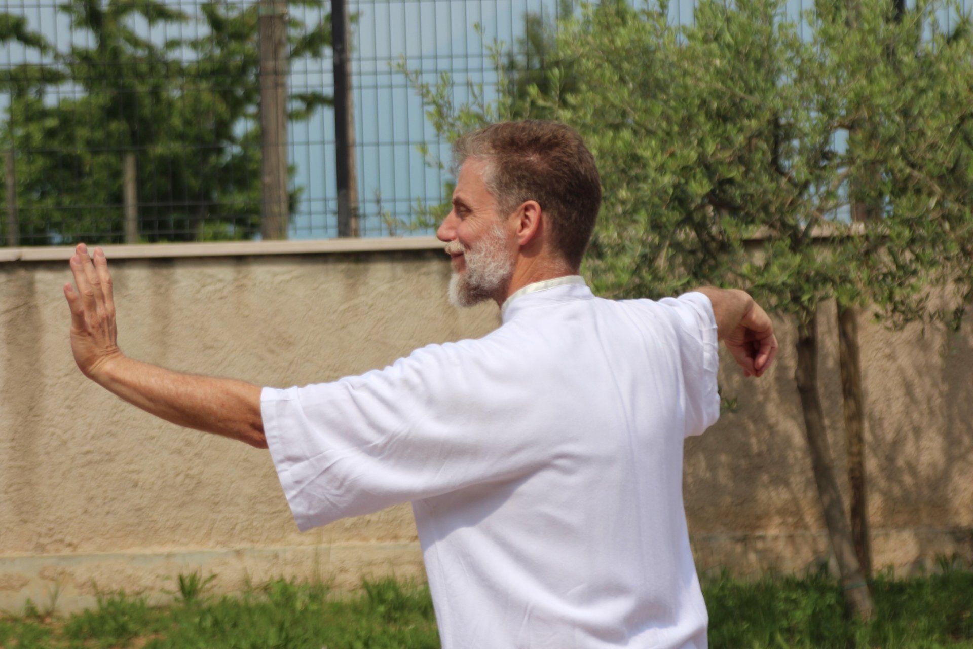 Un uomo con la barba è in piedi davanti a un muro con le braccia tese.