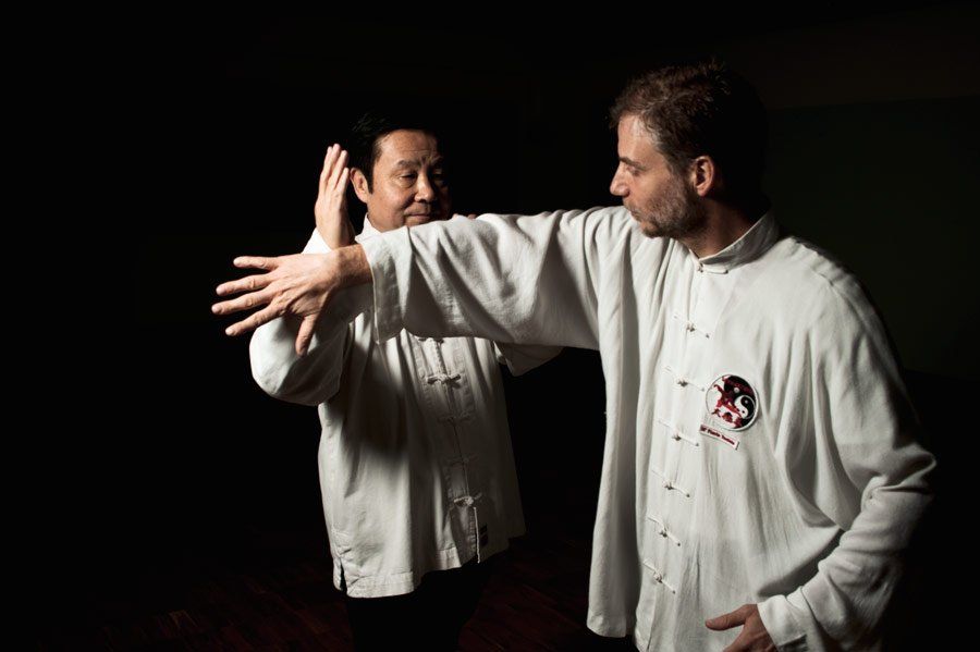 Due uomini praticano le arti marziali in una stanza buia.