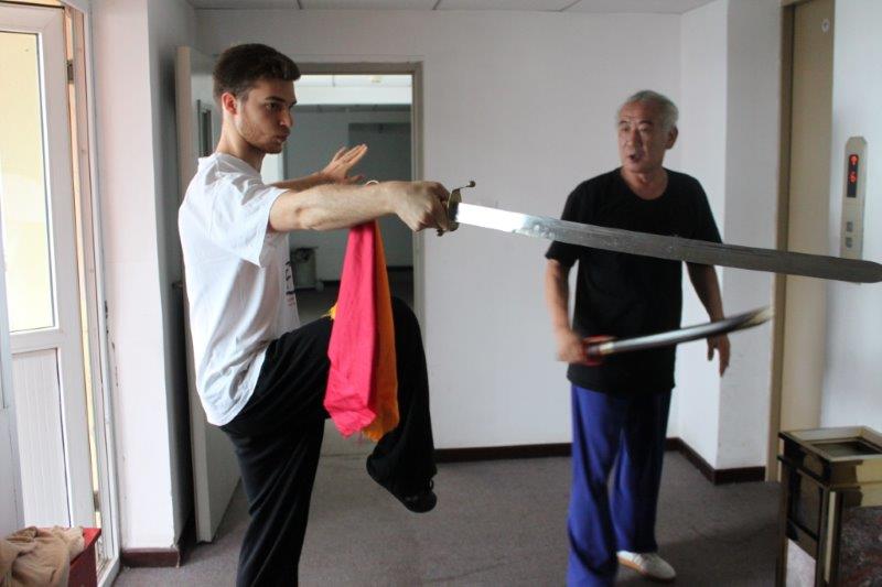 Due uomini praticano arti marziali con le spade in una stanza