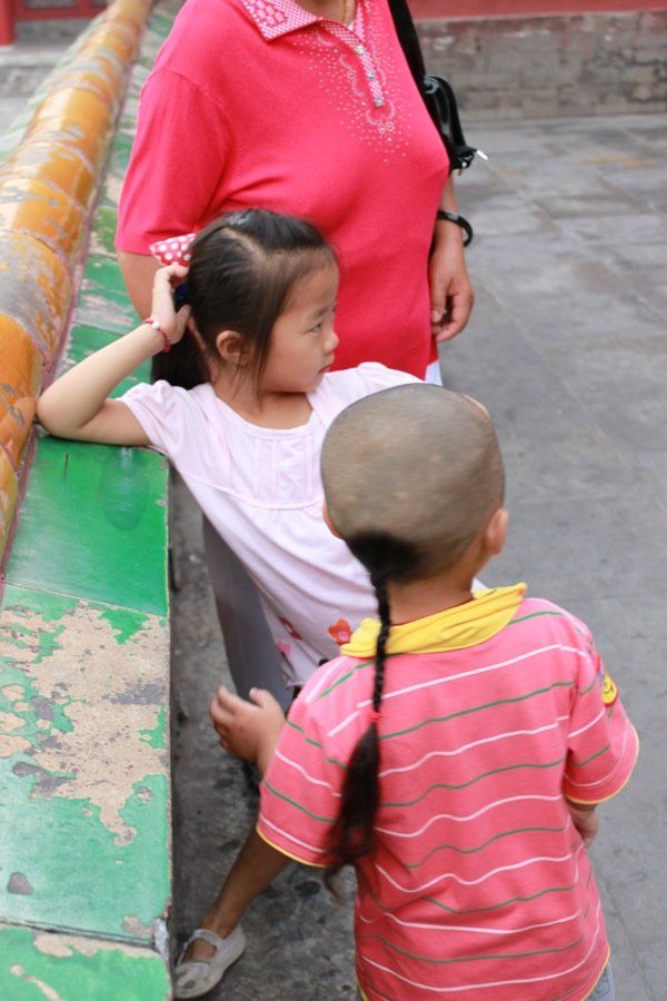 Una donna con una maglietta rosa è in piedi accanto a due bambini
