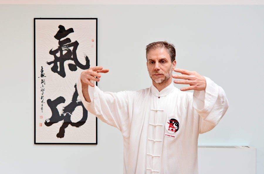 Un uomo è in piedi davanti a un muro con sopra una scritta cinese.