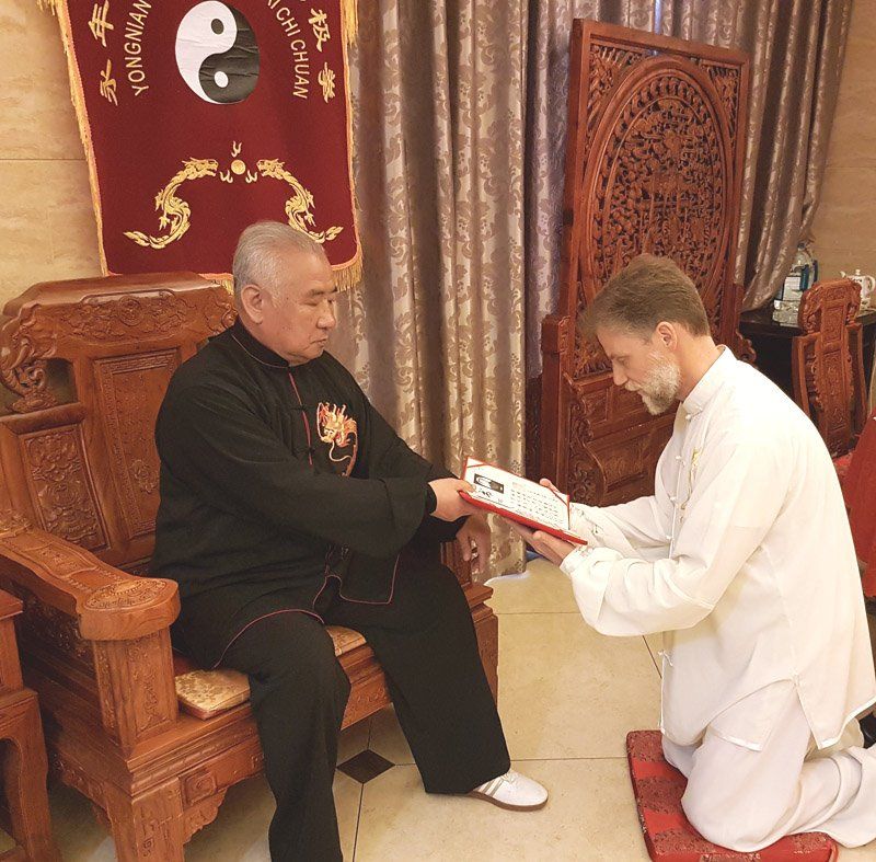 Due uomini sono inginocchiati davanti a un cartello che dice yin yang