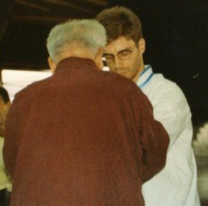 Un uomo con una camicia bianca sta parlando con un uomo più anziano con una giacca marrone
