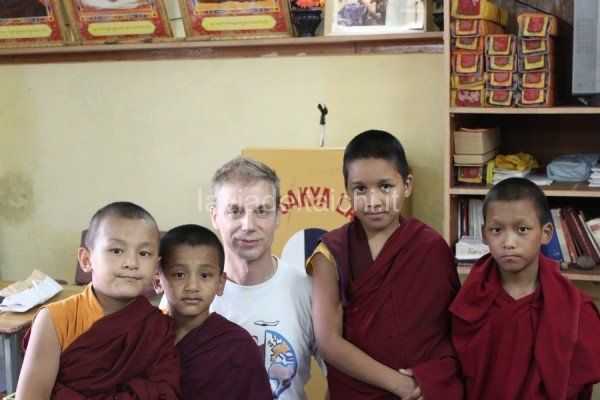 Un gruppo di giovani monaci sta posando per una foto con un uomo con una camicia bianca che dice akya