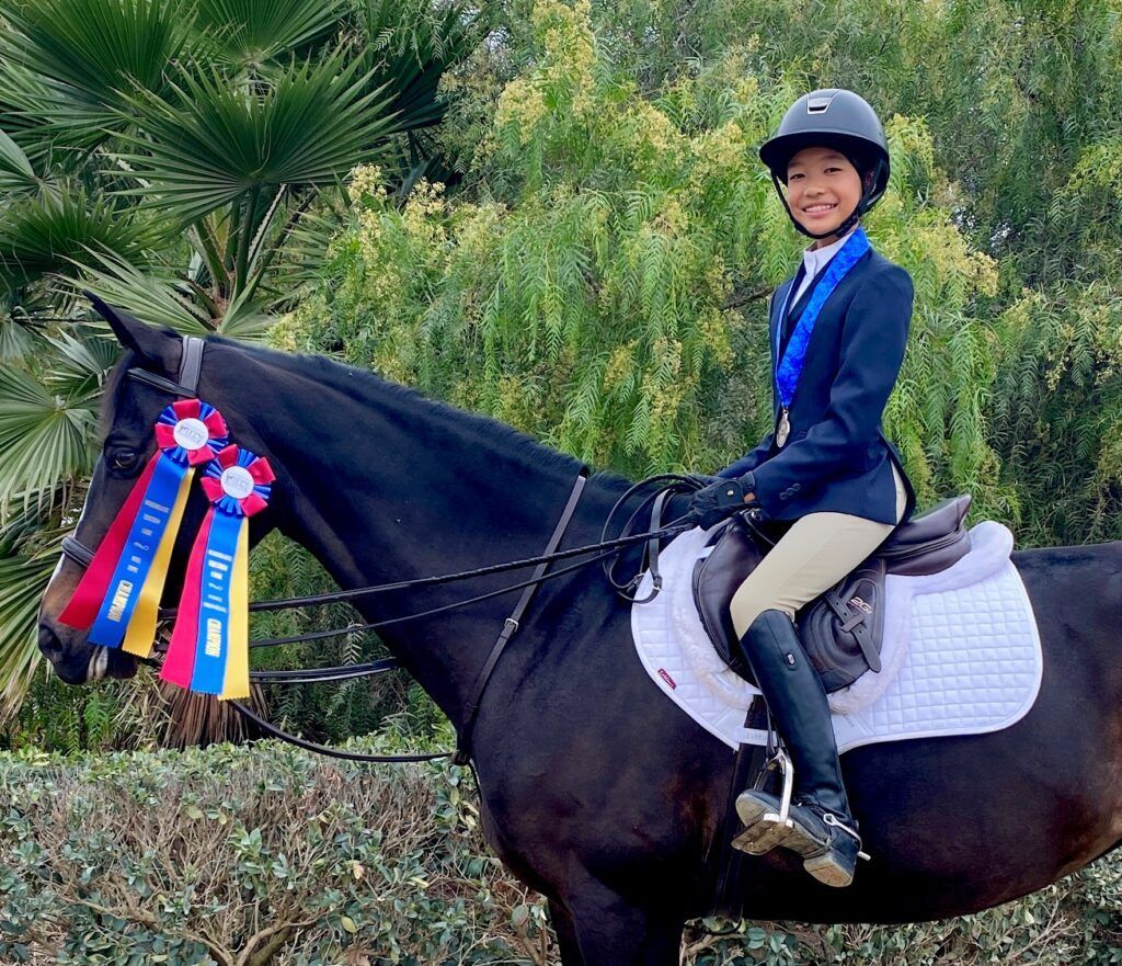 A woman is riding a horse with ribbons on it.