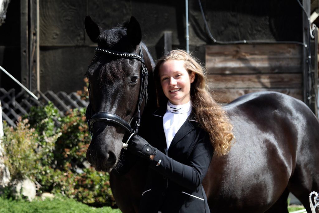 A woman is standing next to a black horse.