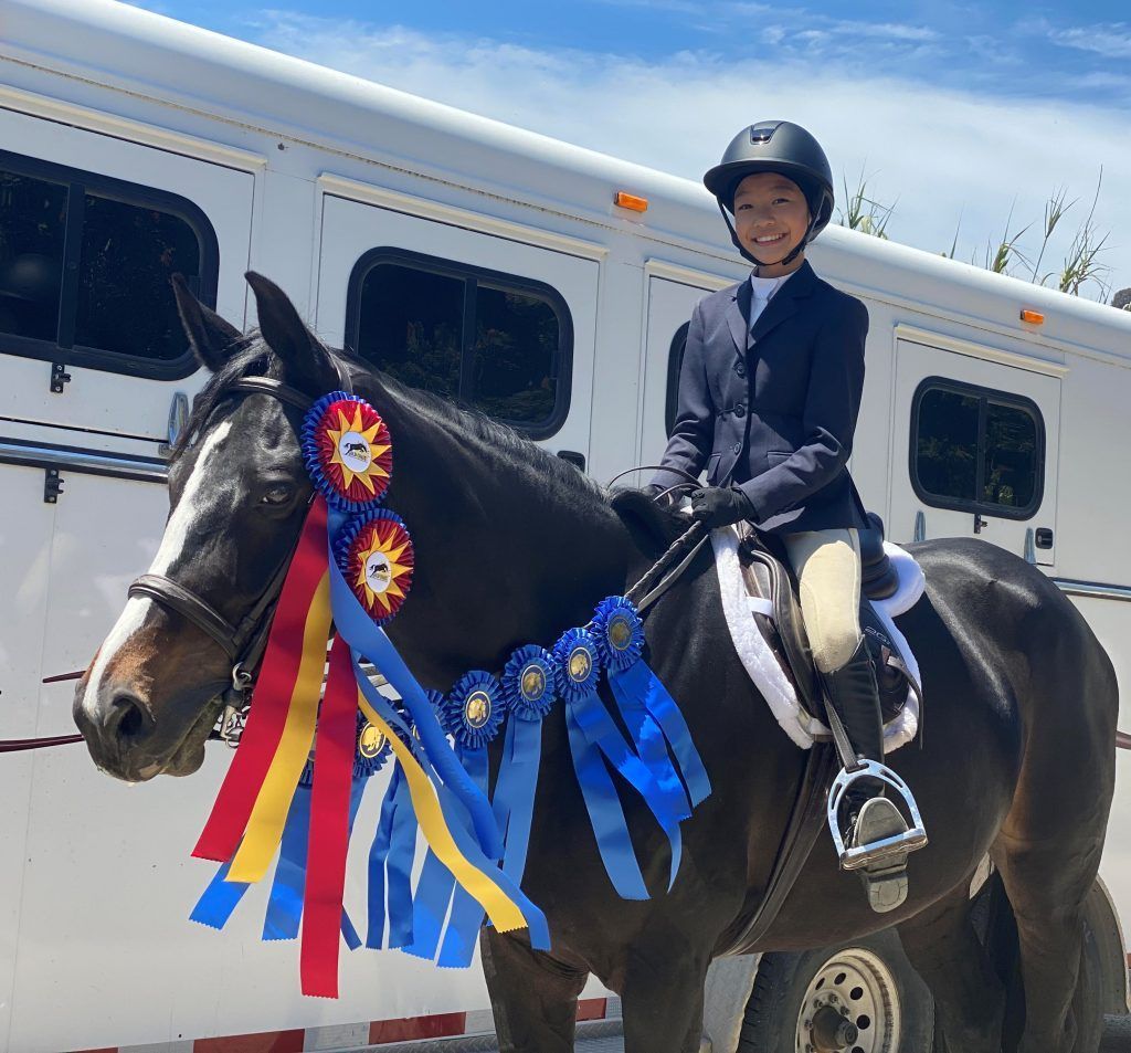 A young boy is riding a horse with ribbons around it.