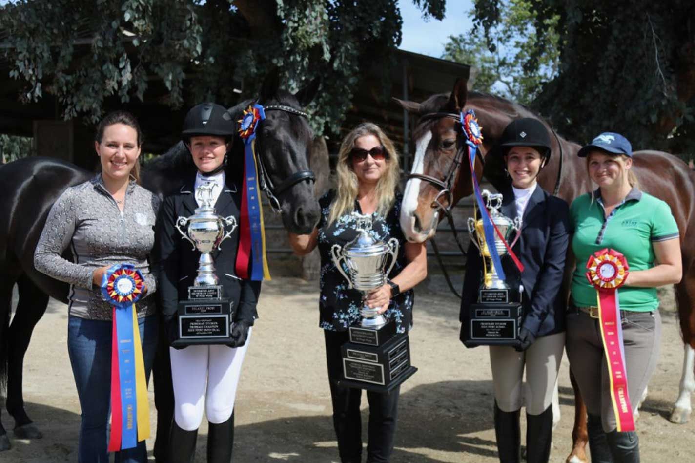 A group of women standing next to horses holding trophies