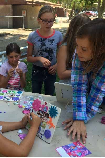 A girl wearing a shirt that says windy hair is sitting at a table with other girls
