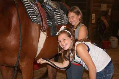 two girls holding a stethoscope to a horse