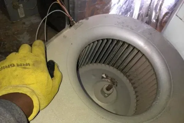 A person wearing yellow gloves is working on a fan.