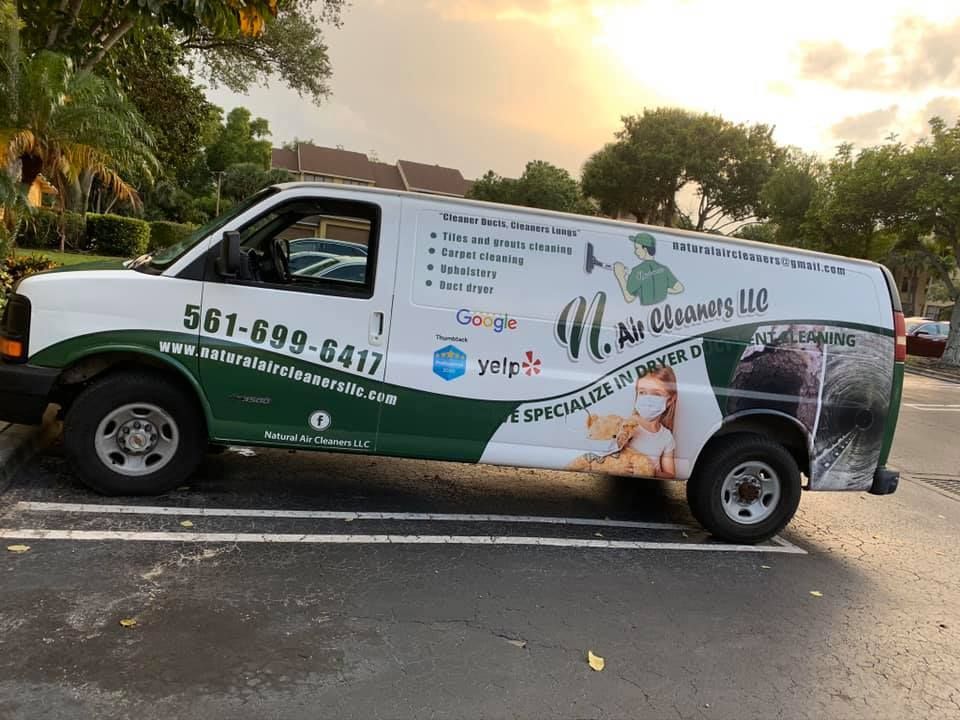 A green and white van is parked in a parking lot.