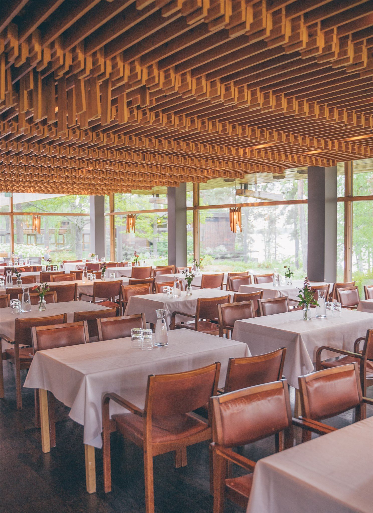 Ravintolan ruokasali, jossa on puinen sälekatto, ruskeat nahkanojatuolit ja vaaleasävyisillä liinoilla peitetyt pöydät.