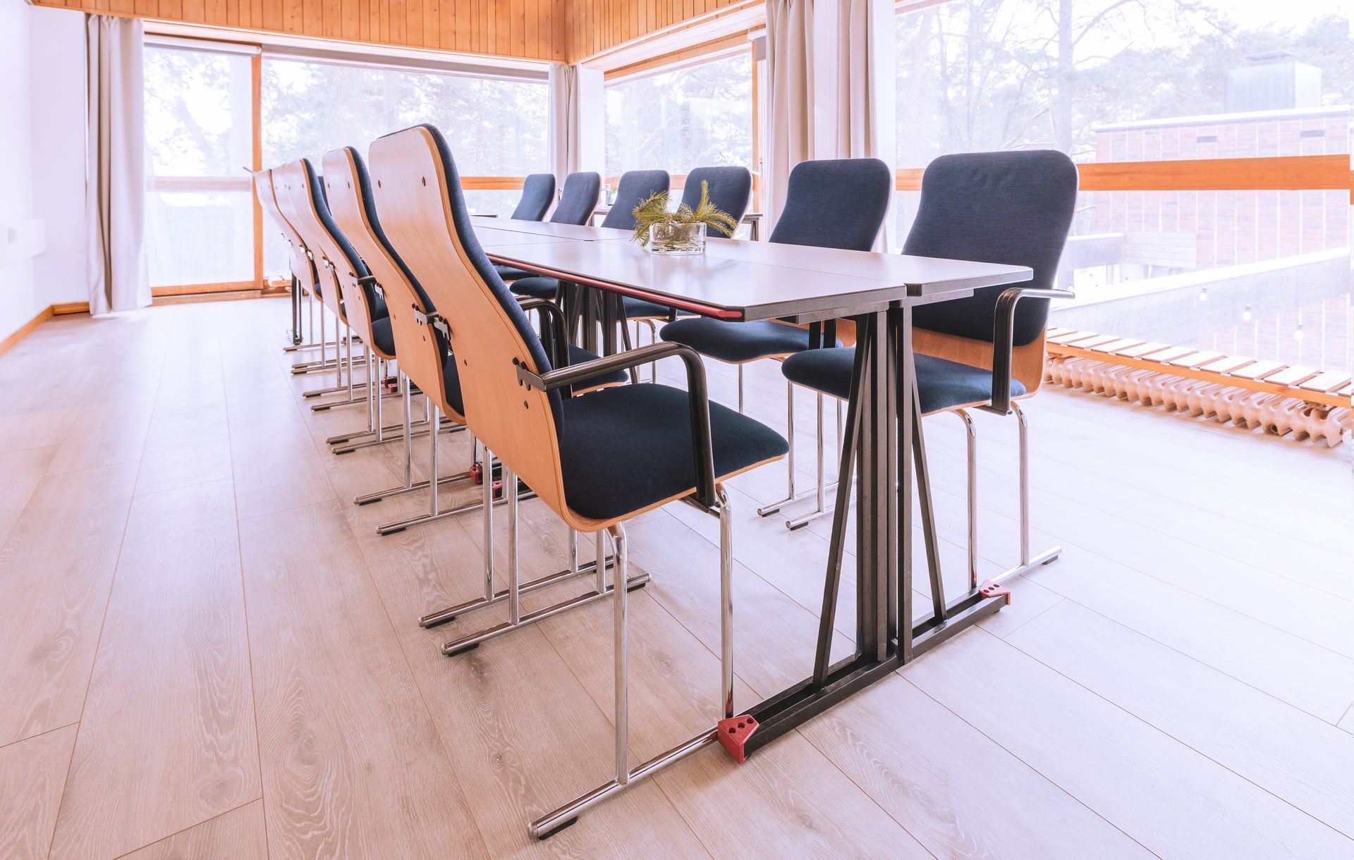 Kokoushuone, jossa on pitkä pöytä ja mustat tuolit kokousta varten suurten ikkunoiden edessä.