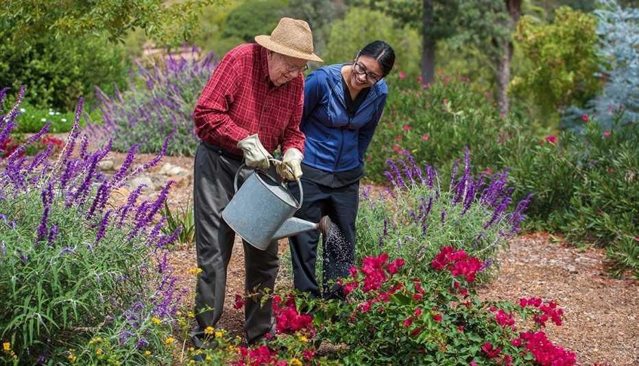 A man and a woman are watering flowers in a garden.