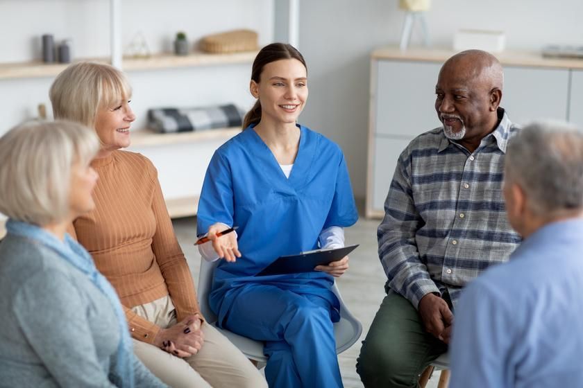 A group of elderly people are sitting in a circle with a nurse.