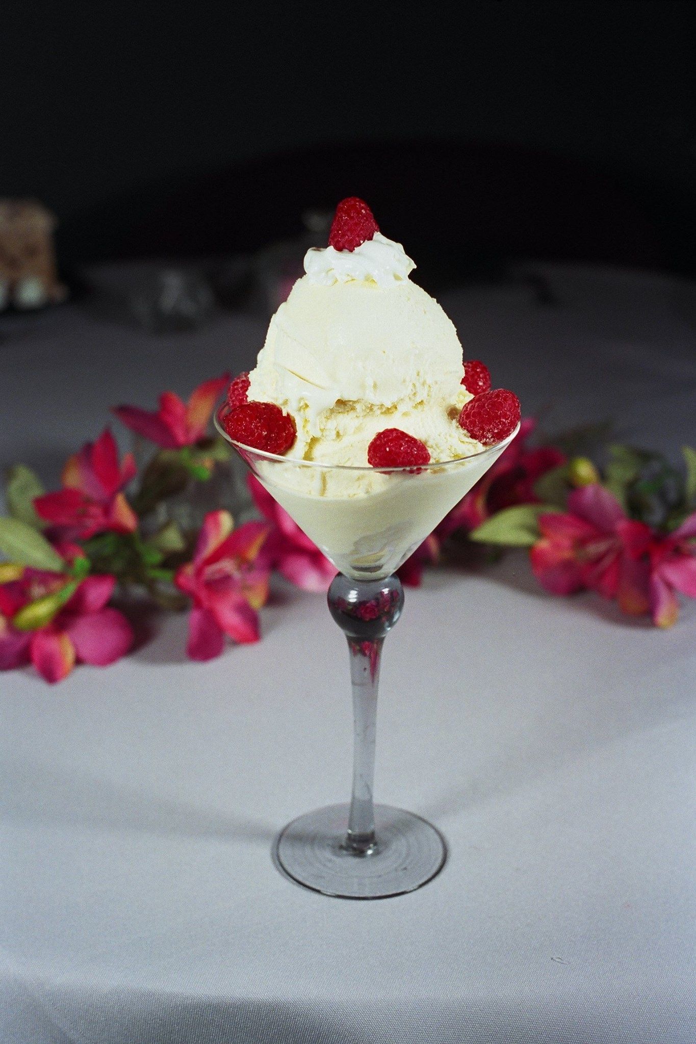 Vanilla ice cream sundae in a glass, with raspberries and whipped cream.