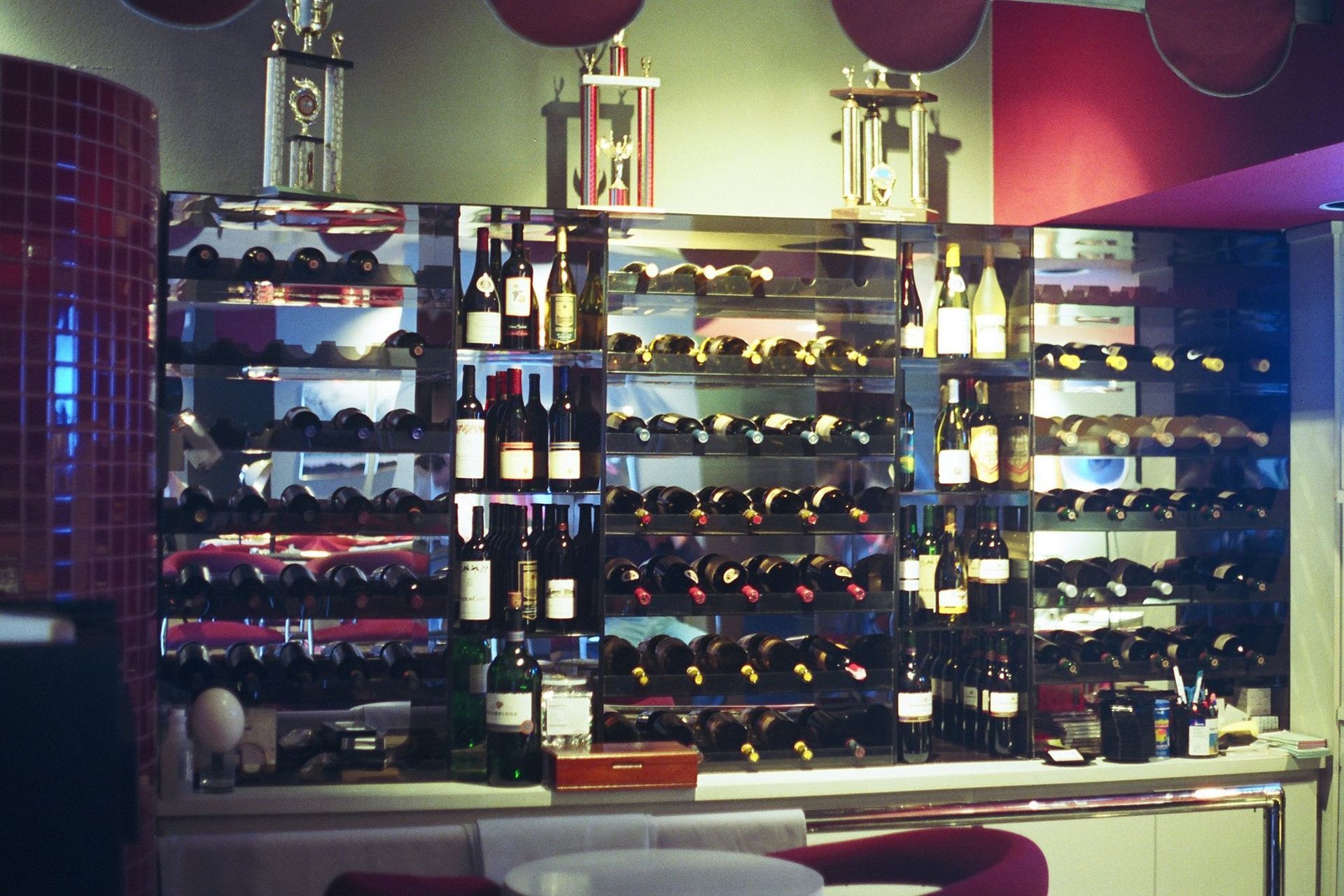Wine bottles displayed on mirrored shelves, possibly a restaurant or bar.