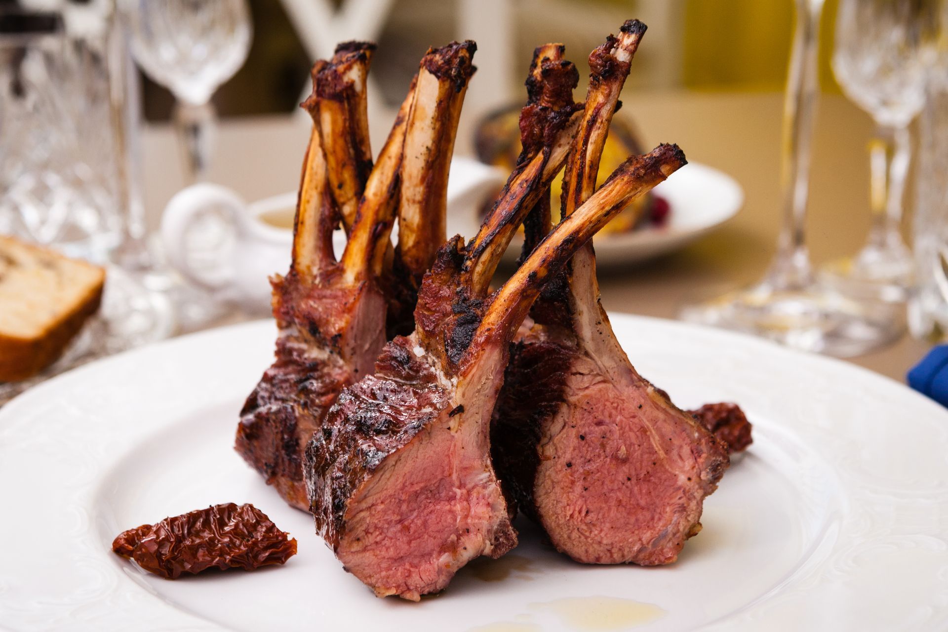 Rack of lamb, cooked with exposed bones, on a white plate.