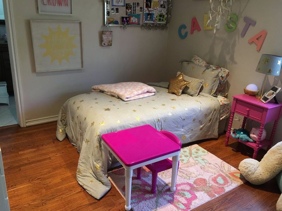 A child's bedroom with bed, pink table/chair, nightstand. Light and airy with wood floors.