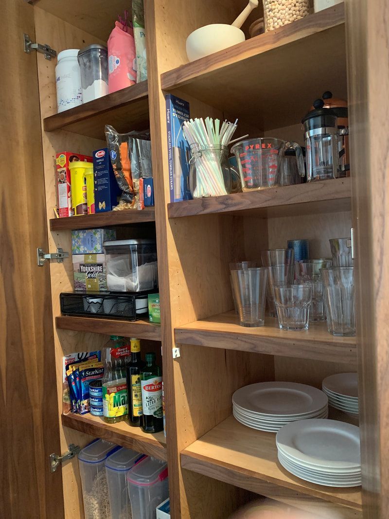 Wooden pantry shelves with food items, glasses, and plates.