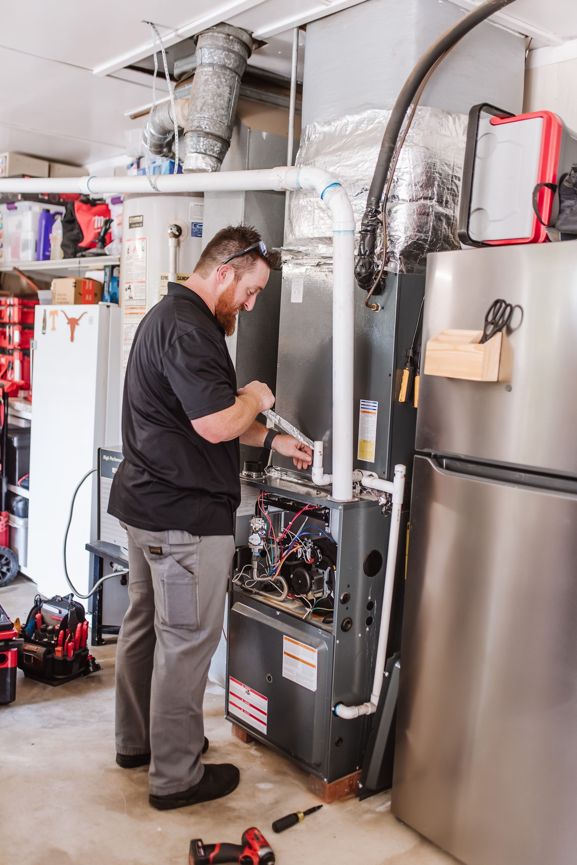 Family laughing together indoors; child on father's shoulders, mother hugging them.