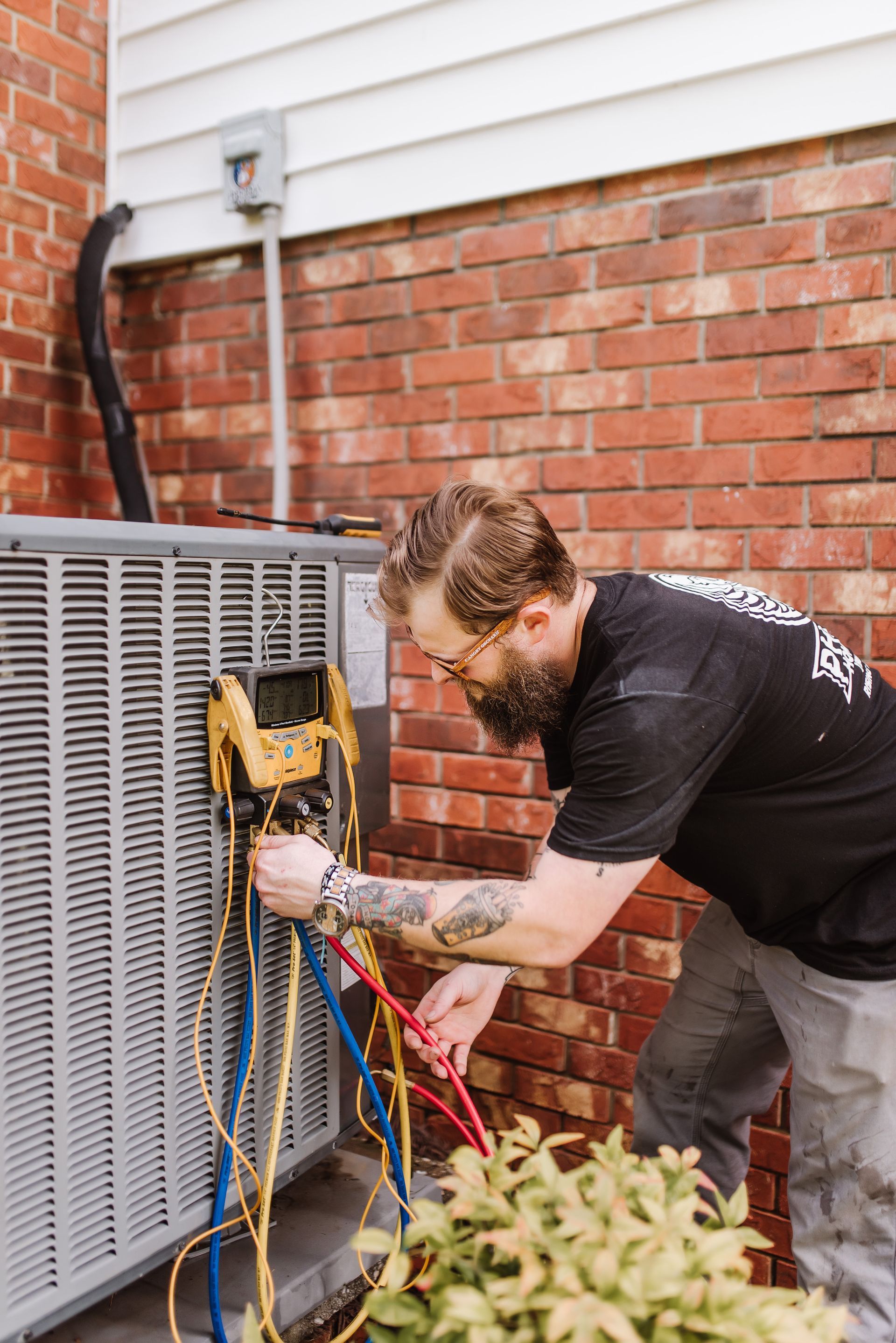 Tool bag with screwdrivers on an air conditioning unit in front of a house.